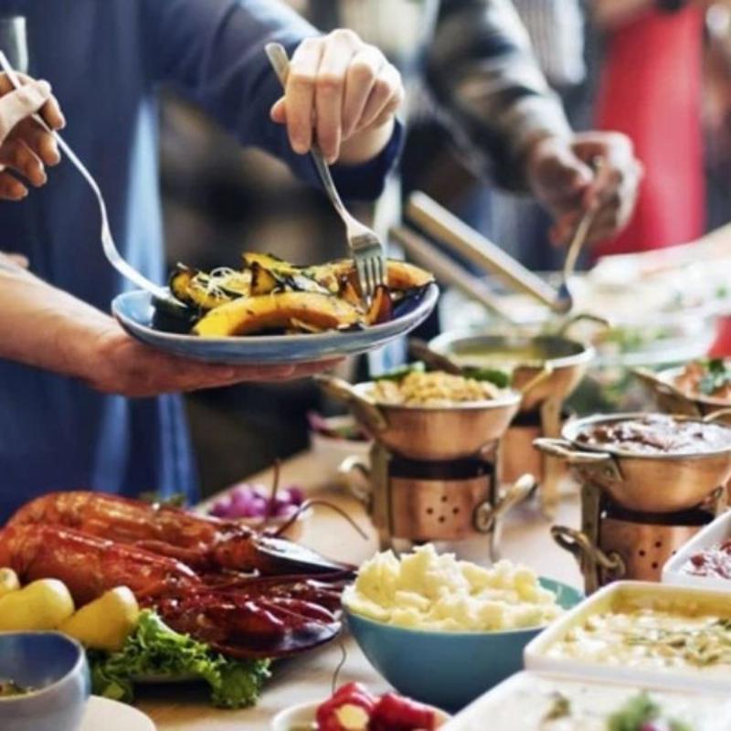 Một gia đình hoặc nhóm bạn đang vui vẻ cùng nhau bóc vỏ hải sản và trò chuyện tại bàn ăn ở một quán ăn hải sản truyền thống